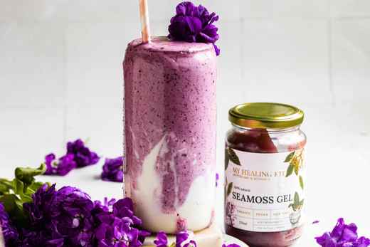 A rich, decadent Blueberry Cheesecake Seamoss Smoothie with layers of vivid purple-blue hues in a glass. 